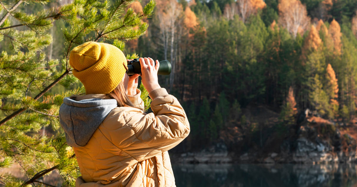 femme dans une forêt regardant à travers de jumelles